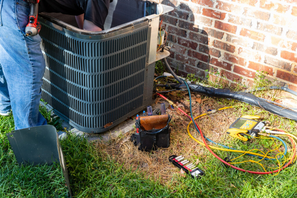 Air conditioner maintenance being performed by an HVAC technician.