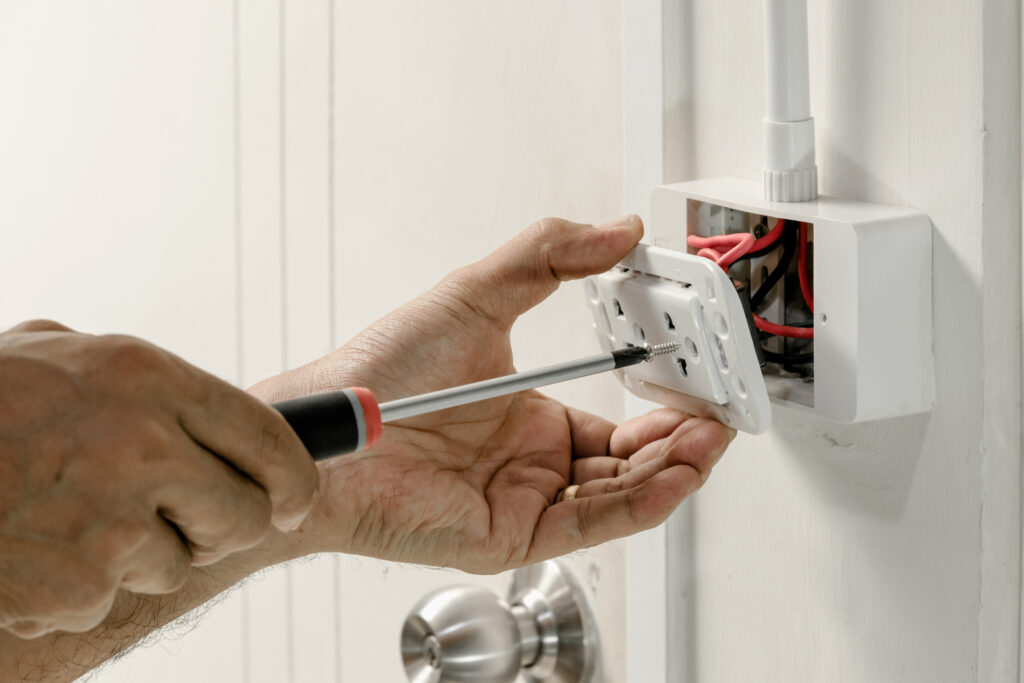 Electrician's hands using a screwdriver to install a new outlet.