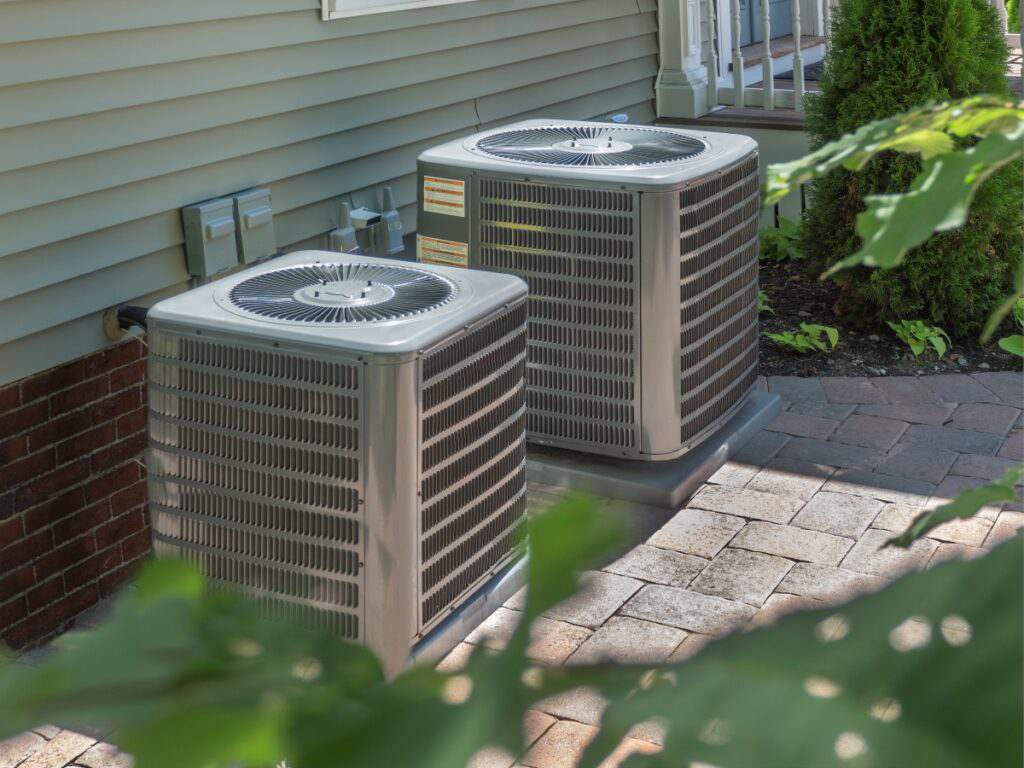 Two residential air conditioners outside of a home