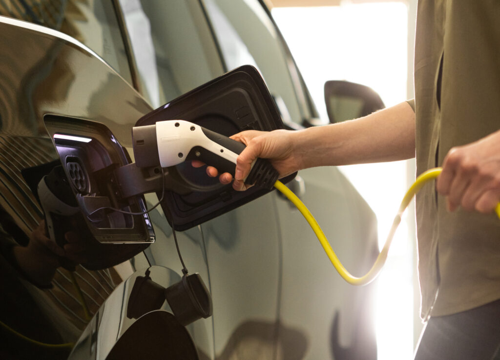 Woman using an EV charger in her garage.