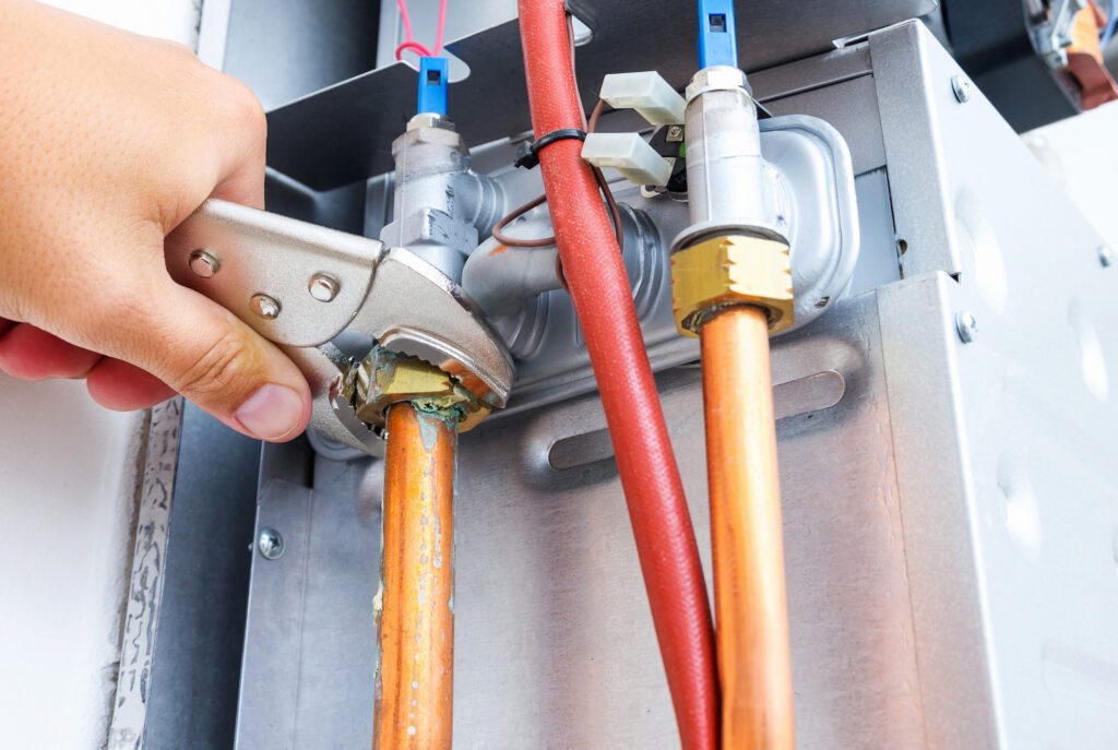 Technician's hands using a tool to repair a furnace.